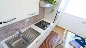 Una cucina compatta con lavello, piano cottura e un ripiano a listelli in legno.