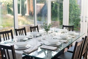 Une table à manger dressée pour six personnes, avec des chaises, un vase rempli de verdure et des bougies.