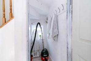 A hallway with a vacuum cleaner, a radiator, and a door leading to another room.