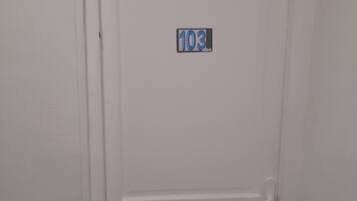 Een witte deur met een nummerbord waarop kamer 103 staat.