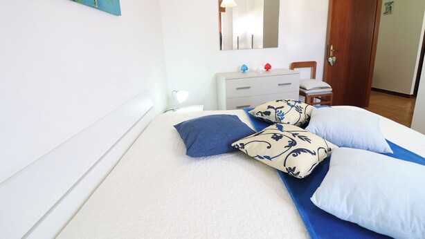 Ein Schlafzimmer mit Bett, Schminktisch, Spiegel und Tür.