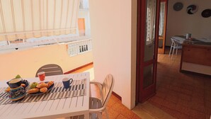 Ein Balkon mit Frühstückstisch, einem Stuhl und Blick ins Innere des Gebäudes.