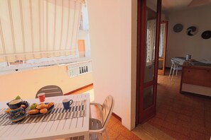 Ein Balkon mit Frühstückstisch, einem Stuhl und Blick ins Innere des Gebäudes.