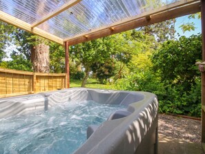 A hot tub under a pergola with a wooden deck and a tree in the background. - Apple Bough Cottage (Hereford)