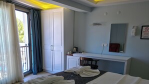 Habitación de hotel con cama, escritorio, espejo y vistas al exterior.