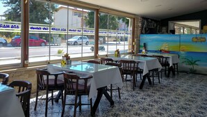 Un restaurante con amplios ventanales, suelo de baldosas y mesas dispuestas para comer.