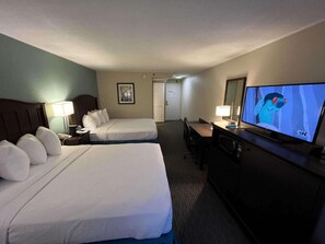 Une chambre d’hôtel avec deux lits, un bureau, une télévision et une porte donnant sur un couloir.