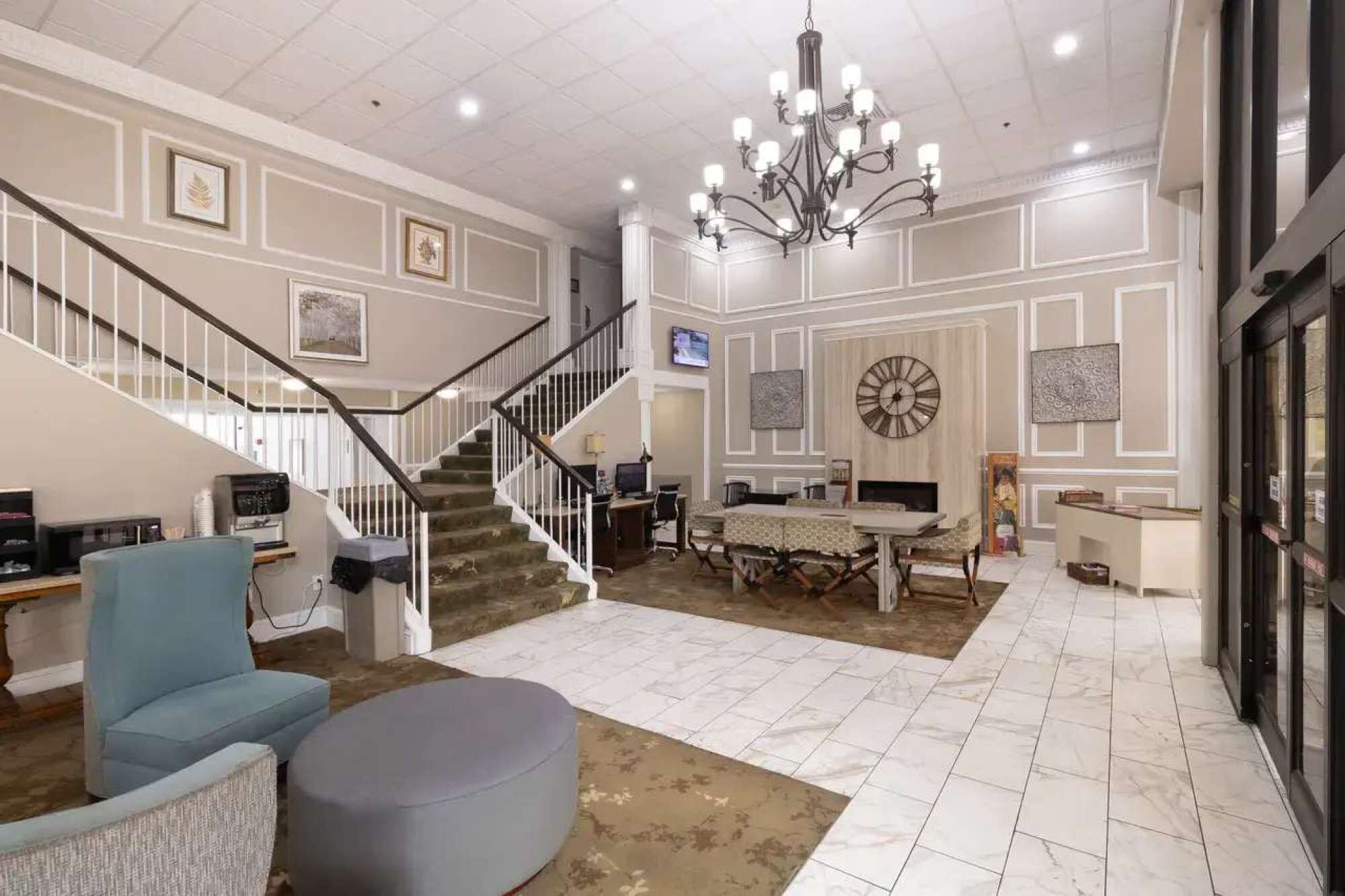 A spacious living area with a staircase, a dining table, and a chandelier.
