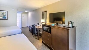 A hotel room with a bed, a desk with a chair, a television, and a dresser. - Pet-Friendly Room | Free Breakfast (Williamsburg)