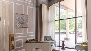 A hotel lobby with a reception desk, seating area, and large windows offering a view of the outdoors. - Pet-Friendly Room | Free Breakfast (Williamsburg)