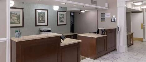 A reception area with marble flooring, framed pictures on the walls, and a counter with a telephone.