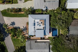Vista aérea de una propiedad residencial con piscina, mobiliario de patio y jardín ajardinado.