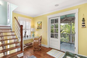 Una escalera lleva a una habitación con vistas al exterior, una mesa con una lámpara y una silla.