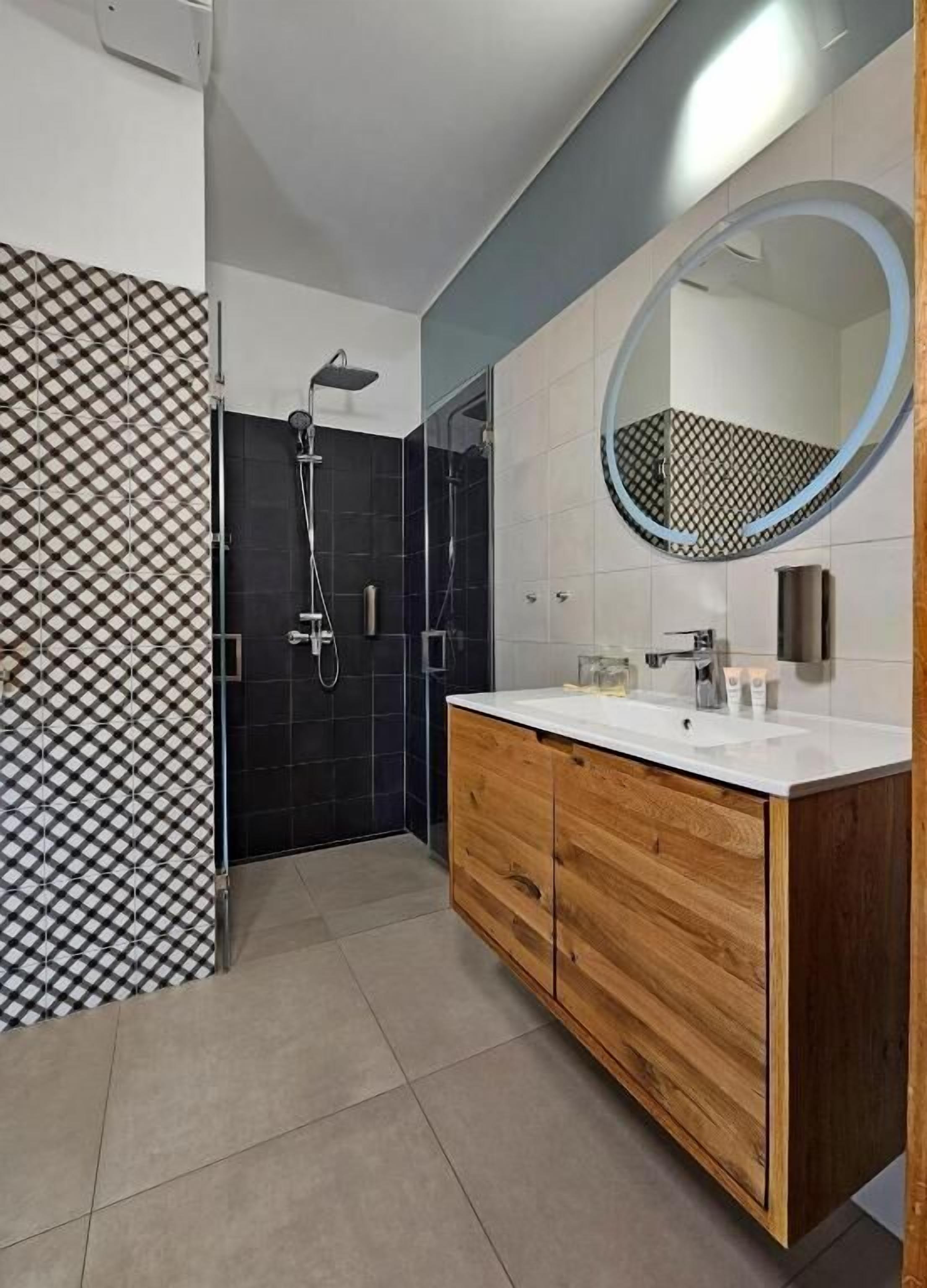 A modern bathroom with a shower, a vanity with a mirror, and patterned tiles.