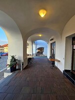 En inomhuskorridor med valv, ett klinkergolv och utsikt över gatan utanför.