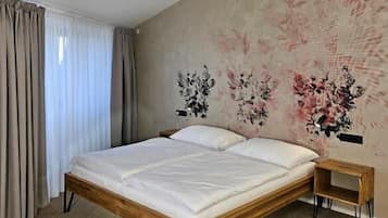 Un dormitorio con cama de madera, lámpara colgante y pared con estampado floral.