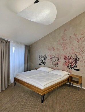 Un dormitorio con cama de madera, lámpara colgante y pared con estampado floral.