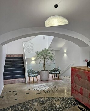 Un interior moderno con una escalera, una planta en maceta y una alfombra redonda.