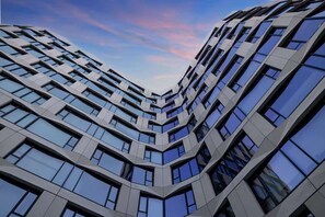 A modern high-rise building with a distinctive angular design and numerous windows. - Steps to Union Square + Rooftop Bar & Gym (San Francisco)