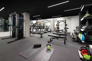 A gym with various exercise equipment including treadmills, weight machines, and free weights. - Steps to Union Square + Rooftop Bar & Gym (San Francisco)