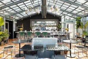 A modern bar area with a glass ceiling, green chairs, and a marble bar counter. - Steps to Union Square + Rooftop Bar & Gym (San Francisco)