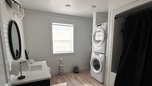 A modern bathroom with a sink, mirror, and two stacked washing machines.