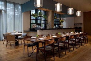 A modern dining area with a long wooden table set for a meal, surrounded by chairs. - Close to Moscone Center + Rooftop Restaurant & Bar (San Francisco)