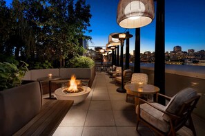 An outdoor seating area with a fire feature, tables, and chairs, overlooking a cityscape. - Close to Moscone Center + Rooftop Restaurant & Bar (San Francisco)