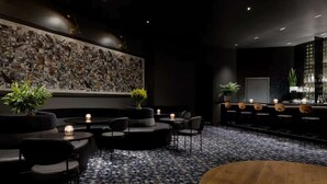 Un espace bar moderne avec un sol à motifs, des meubles noirs et un mur décoré d’illustrations d’oiseaux.