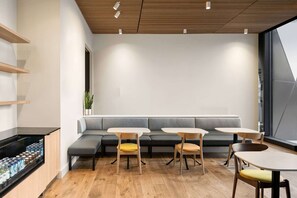 A modern interior with a wooden ceiling, a grey sofa, and wooden tables and chairs. - Close to Union Square + Rooftop Restaurant & Bar (San Francisco)