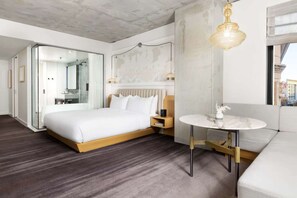 A modern hotel room with a large bed, a bedside table, a small round table, and a sofa. - Close to Union Square + Rooftop Restaurant & Bar (San Francisco)