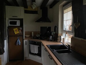 A compact kitchen with a microwave, stove, kettle, and coffee maker. - The Enchanted Cottage (Saint-Christophe-sur-Condé)