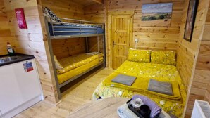 A compact room with bunk beds, a small kitchenette, and a bed with floral bedding. - Bluebell Lodge Dog Friendly, nr Anderby Creek (Alford)