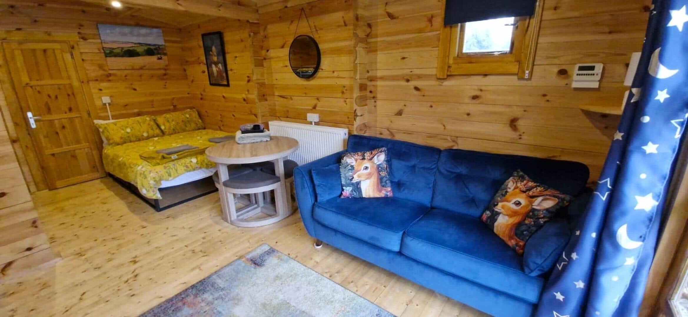 A wooden cabin interior with a sofa, a small round table, and a chair.