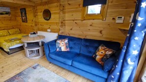A wooden cabin interior with a sofa, a small round table, and a chair. - Bluebell Lodge Dog Friendly, nr Anderby Creek (Alford)