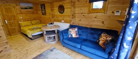 A wooden cabin interior with a sofa, a small round table, and a chair.