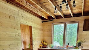 Ein Holzblockhaus-Innenraum mit Essbereich, Küche und großen Fenstern.