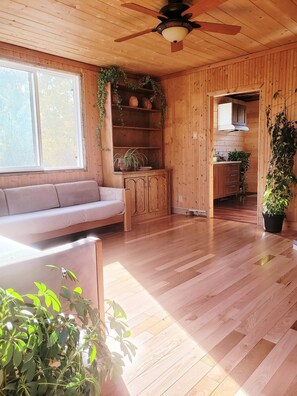 A wooden interior with a sofa, a cabinet, and a ceiling fan.