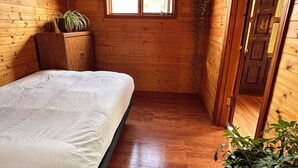 Ein Zimmer mit Holzboden, einem Bett, einem Fenster und einer Tür.