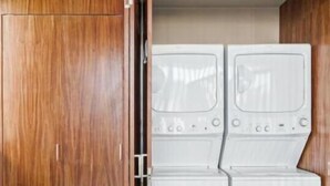 A room with a wooden wardrobe and a built-in washer and dryer unit. - Ocean Boutique Condos (Playa del Carmen)