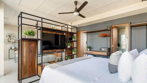A modern bedroom with a bed, a TV, a desk, and a wardrobe. - Ocean Boutique Condos (Playa del Carmen)