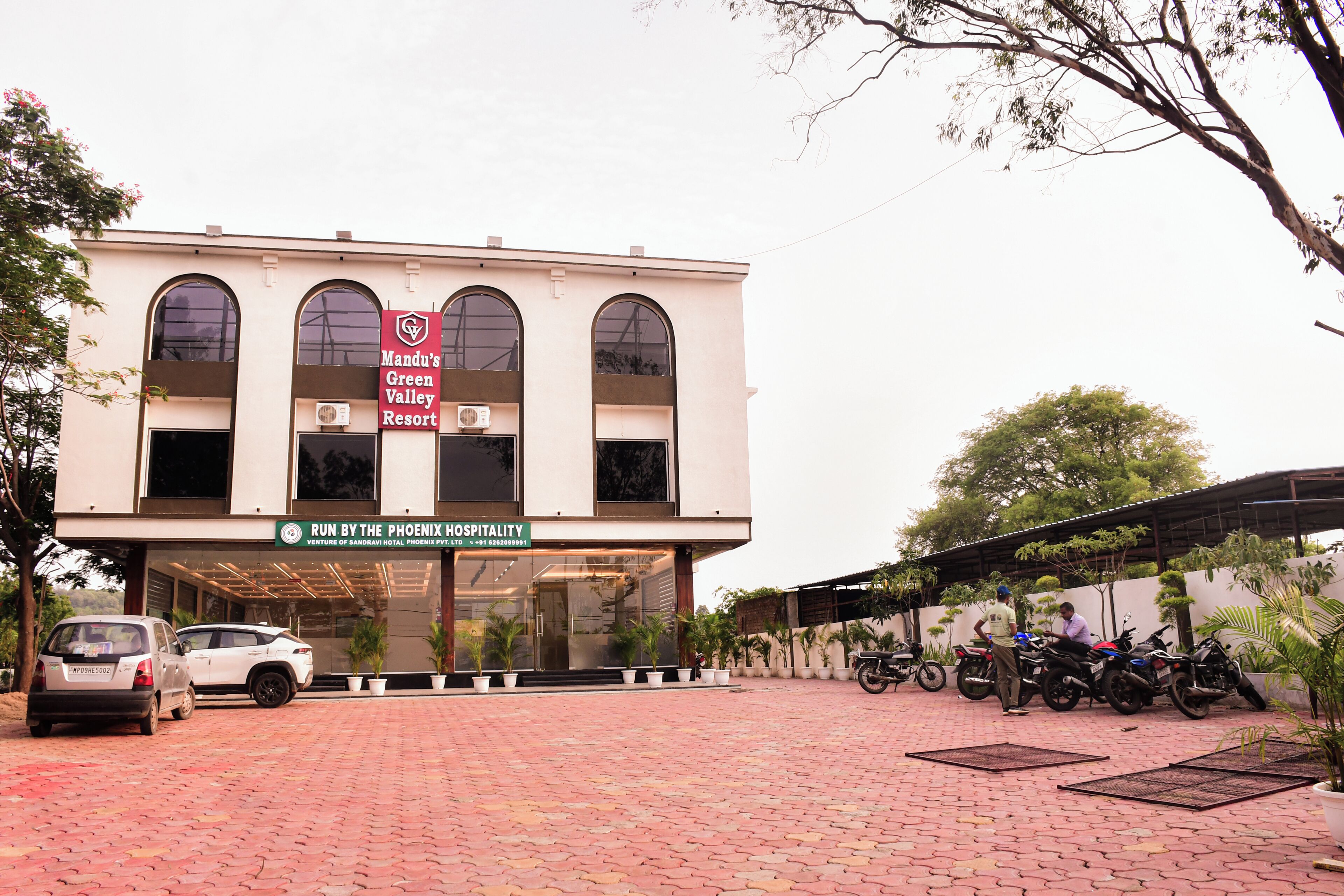 A building with a sign for Mandu's Green Valley Resort and Run by the Phoenix Hospitality.