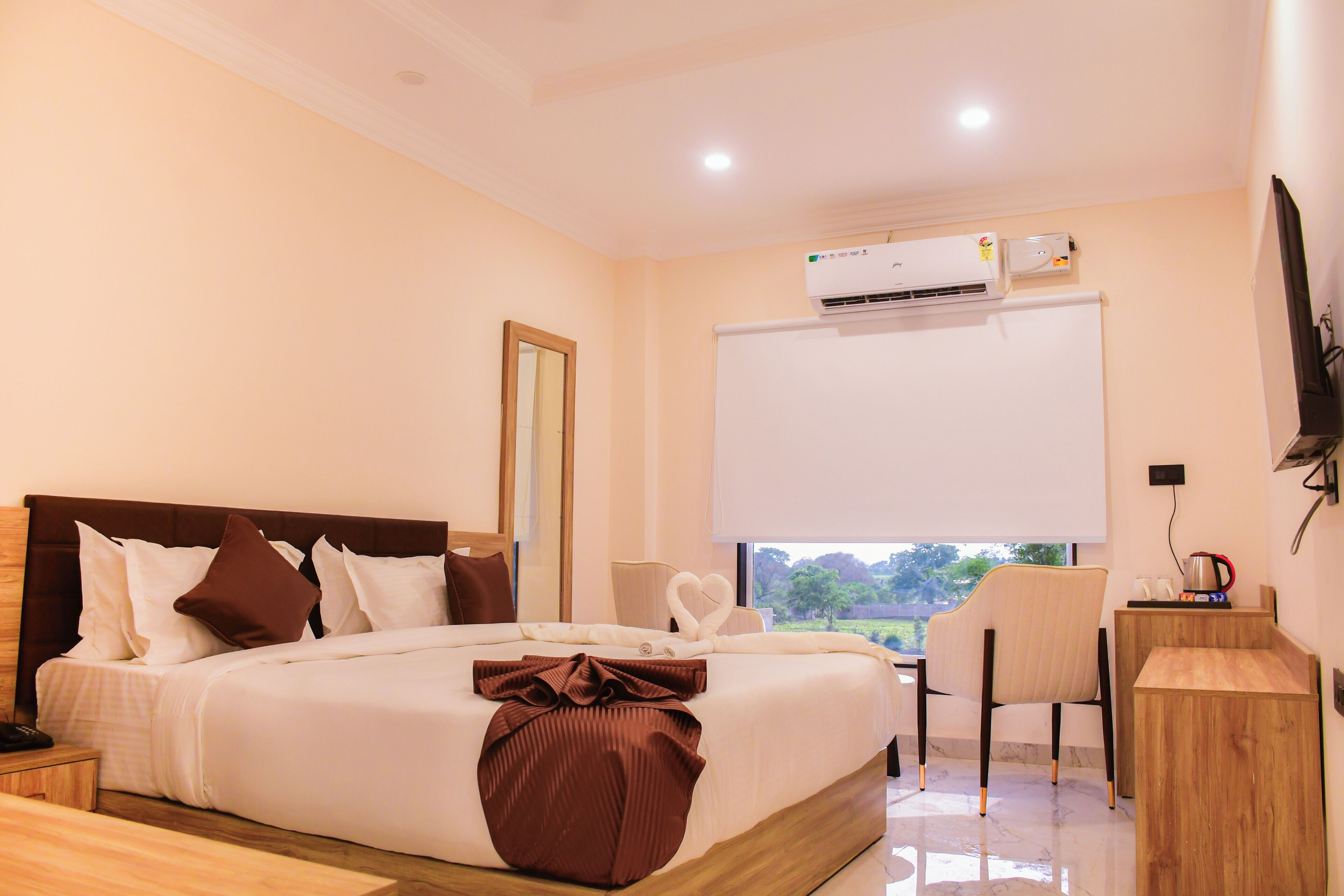 Habitación de hotel con cama, escritorio, silla, aire acondicionado y televisor.