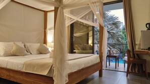 A bedroom with a four-poster bed, a balcony with a view of palm trees, and a small table with glasses. - LE KEPARANGA (Mbour)