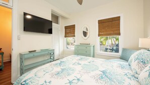Ein Schlafzimmer mit Bett, Fernseher, Kommode und einem Fenster mit Blick.