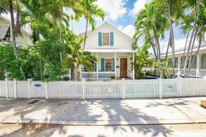 A white house with green shutters, a white picket fence, and palm trees. - Beach Therapy Your Historic Florida Cottage Escape in Key West (Key West, FL 33040)