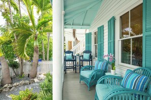 A porch with wicker furniture and a view of a white building with teal shutters. - Beach Therapy Your Historic Florida Cottage Escape in Key West (Key West, FL 33040)