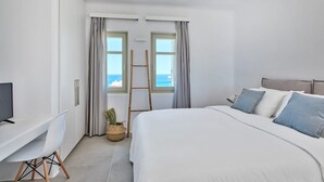 A bedroom with a bed, a desk, a TV, a ladder, and a view of the sea. - Villa Corenyth, Divine Sea Views, Private Furnished Terrace, Shared Pool,. (Mykonos)