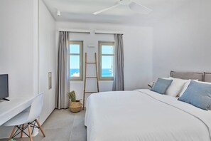Ein Schlafzimmer mit Bett, Schreibtisch, Fernseher, einer Leiter und Blick aufs Meer.