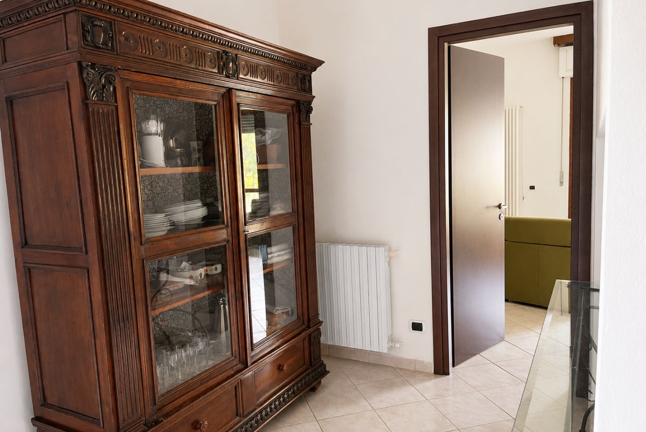 Une pièce comprenant un grand meuble en bois, un radiateur et une porte donnant sur une autre pièce.